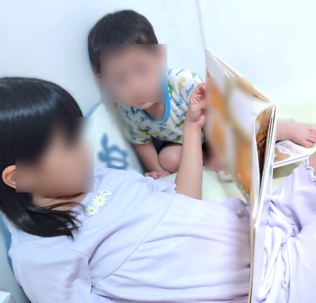 次女が末っ子に本を読み聞かせている写真