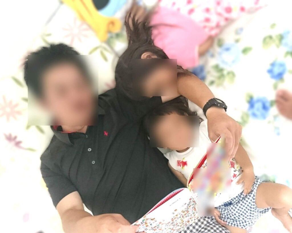 親が、子どもたちに本を読み聞かせている写真